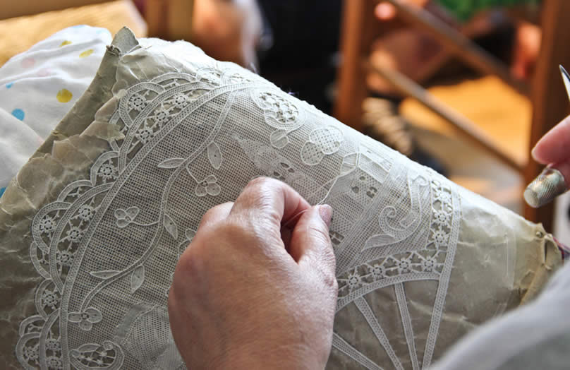 Encajera trabajando una pieza floral presentada por los museos de Venecia