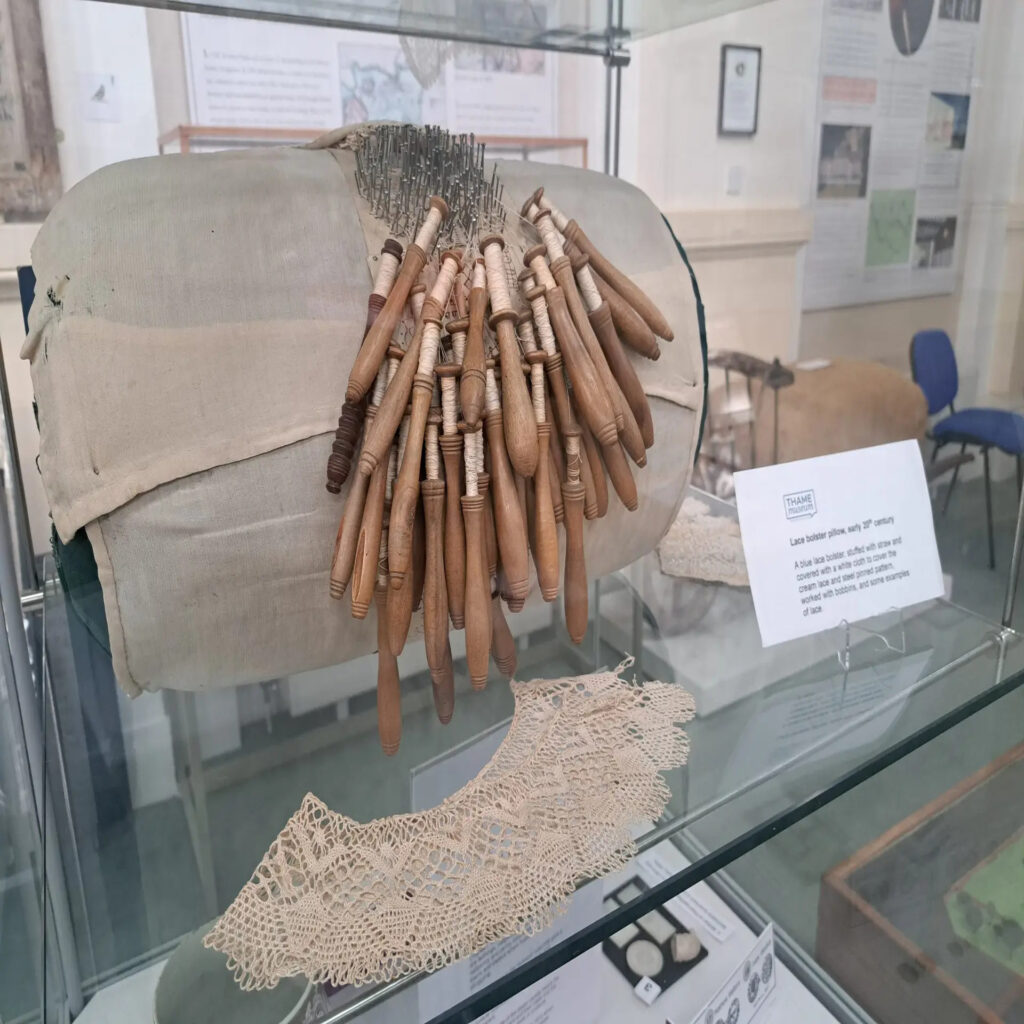 Mundillo cilíndrico histórico con bolillos y una labor en proceso