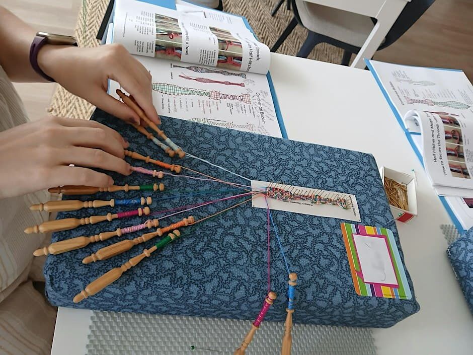 Participante trabajando con bolillos durante un taller para principiantes