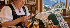 Encajera trabajando con bolillos ante las montañas de Château-d’Œx