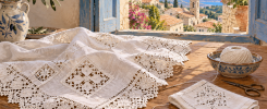 Encaje blanco de Lefkara sobre lino junto a un paisaje mediterráneo